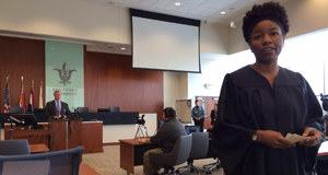 A protester starts a "mock trial" during St. Louis County Prosecuting Attorney Bob McCulloch's speech, as McCulloch continues his speech on the grand jury process in the background. Photo by: CATHERINE MARTIN