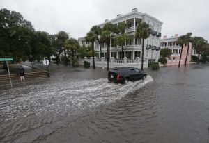 In this Oct. 3, 2015, file photo, a driver takes his truck through a flooded street in Charleston, S.C. Historic coastal cities in the Southeast U.S. have survived disease outbreaks, wars and hurricanes over the past three centuries. Now they are trying to figure how to survive rising seas from climate change. AP Photo by Chuck Burton