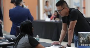 In this Oct. 1, 2019, file photo, Gabriel Picon, right, talks with a representative from GameStop during a job fair at Dolphin Mall in Miami. On Friday, Jan. 10, the U.S. government issues the December jobs report. AP Photo by Lynne Sladky
