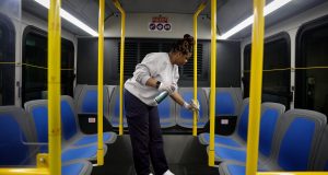 Stacy Loggins, a janitorial supervisor for Metro, wipes down the interior of a bus with disinfectant Thursday at a Metro facility in St. Louis. States across the U.S. are allocating hundreds of millions of dollars to respond to the coronavirus, even as the U.S. government prepares to send billions more their way. Photo by Christian Gooden of the St. Louis Post-Dispatch via AP